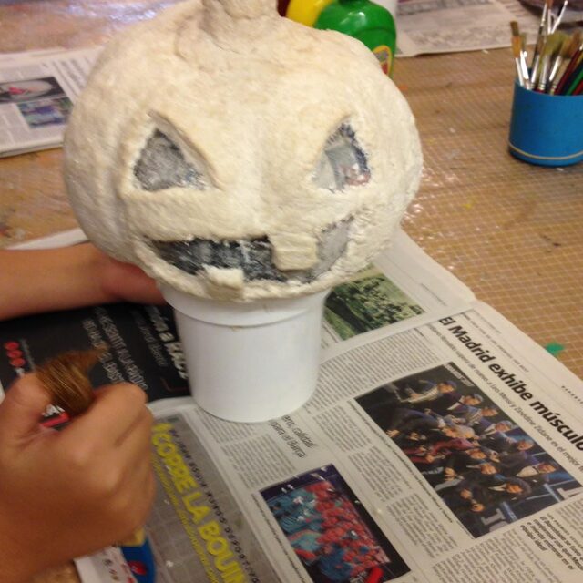 Nens pintant una carbassa de paper maixé per Halloween